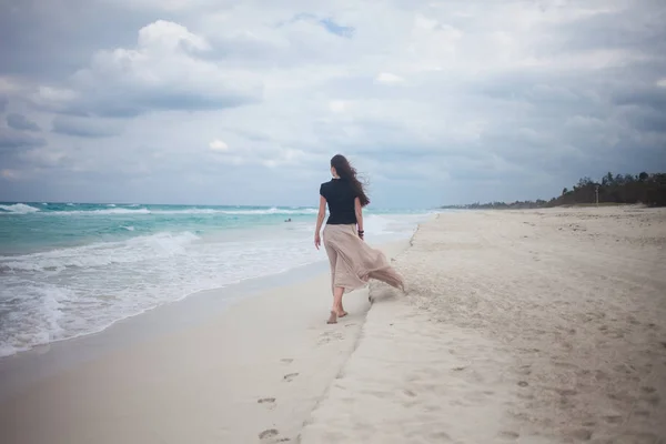 Jonge vrouw in een lange rok die lopen op de Oceaan. — Stockfoto