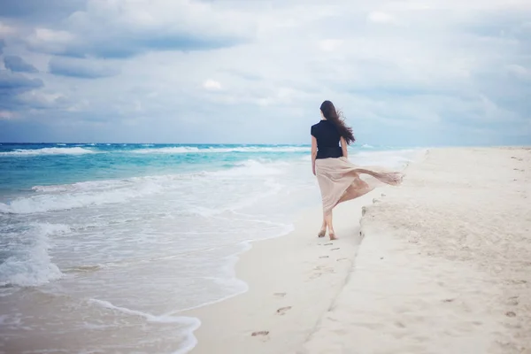 Ung kvinde i en lang nederdel gå på havet . - Stock-foto