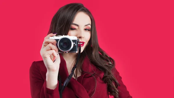 Trendy blogger use the camera on pink background. Young woman with camera