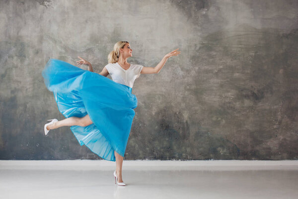 Beautiful young woman in a lush blue skirt, whirling and dancing. Summer style