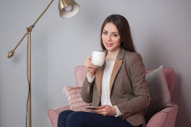 Büyüleyici iş esmer bir sandalyede oturuyor ve bir akıllı telefon sohbet ceketli