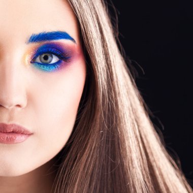 Parlak şık makyajlı çekici esmer. Renkli Smokey eyes ve mavi kaşları.