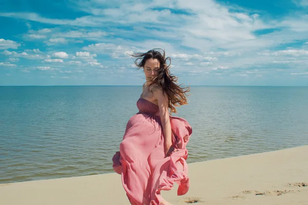 Mujer en vestido ondulante rojo con tela voladora se ejecuta en el fondo de las dunas . — Foto de Stock