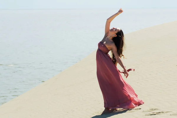 Femme en robe rouge ondulée avec tissu volant fonctionne sur les dunes — Photo