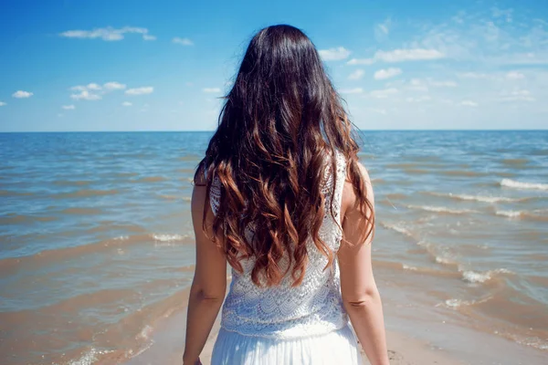Mladá krásná brunetka žena v bílých šatech na břehu moře. — Stock fotografie
