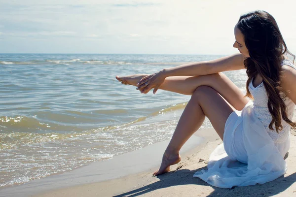 Μελαχρινή όμορφη νεαρή γυναίκα με λευκό φόρεμα στην παραλία. — Φωτογραφία Αρχείου
