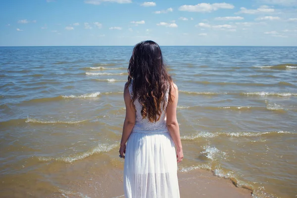 Joven mujer morena hermosa en vestido blanco en la orilla del mar . — Foto de Stock