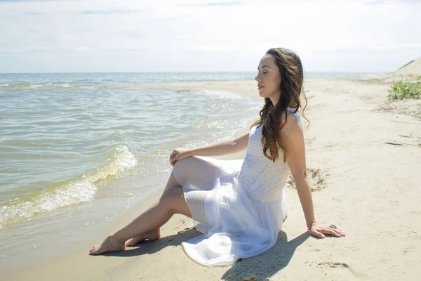 Joven mujer morena hermosa en vestido blanco en la orilla del mar . —  Fotos de Stock