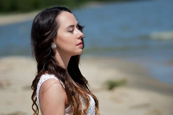 Giovane bella donna bruna in abito bianco sulla riva del mare . — Foto Stock