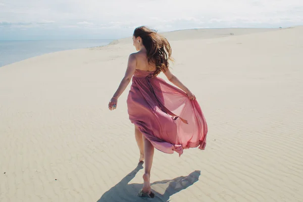 Woman in red waving dress with flying fabric runs far away, back view. — Stock Photo, Image