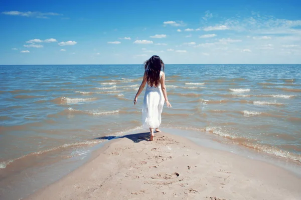 Mladá krásná brunetka žena v bílých šatech na břehu moře. — Stock fotografie