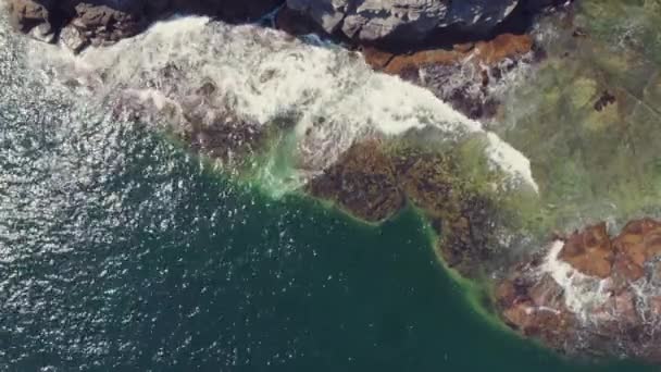 海の中の急な岩の崖の劇的なビュー。青い海と岩の多い海岸、ドローンのすばらしい眺め — ストック動画