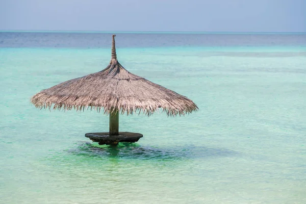 Paraguas de paja en el agua, espacio libre a la derecha. Resort en una isla tropical — Foto de Stock