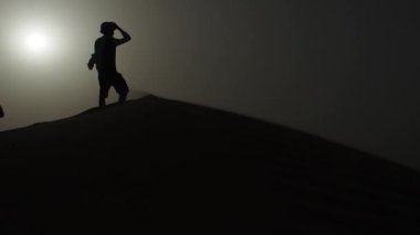 siluet bir kumul üstüne bir adam, çöl. Şapkalı kumun üzerinde duran bir adam Gezgin
