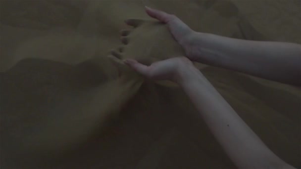 Zand door de vingers. Woestijn. De jonge vrouw schepte het zand met haar handen — Stockvideo