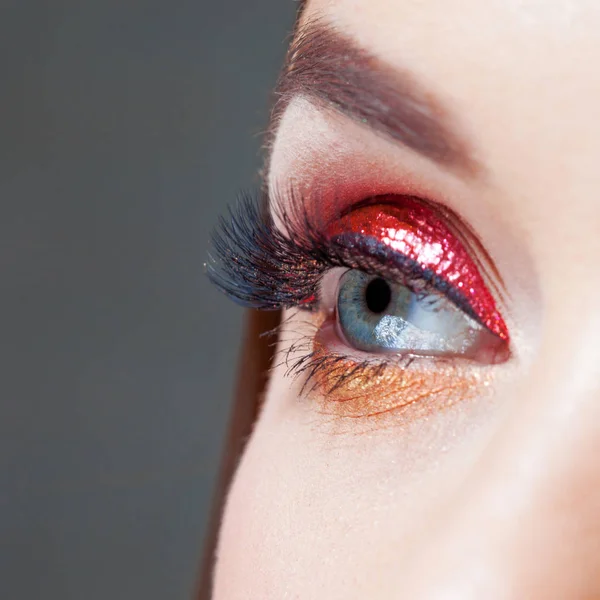 Amazing Bright eye makeup in luxurious red arrow. Red and gold shining tones, eye shadow. — Stock Photo, Image