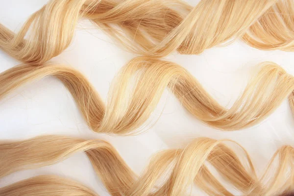 Cachos enrolados no ferro de ondulação, isolados sobre fundo branco. fio de cabelo loiro, cuidado do cabelo — Fotografia de Stock