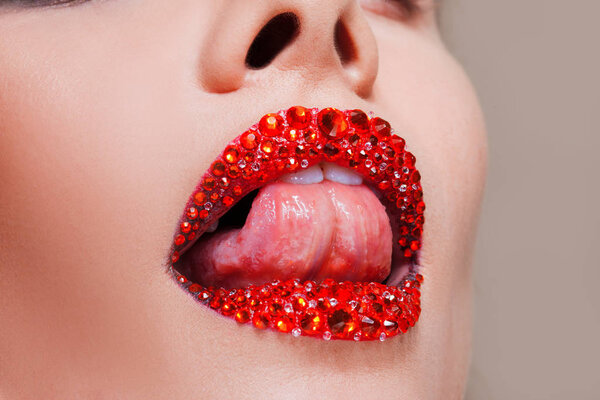 Red lips covered with rhinestones. Beautiful woman with red lipstick on her lips