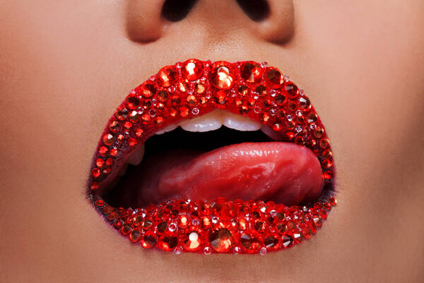 Red lips covered with rhinestones. Beautiful woman with red lipstick on her lips