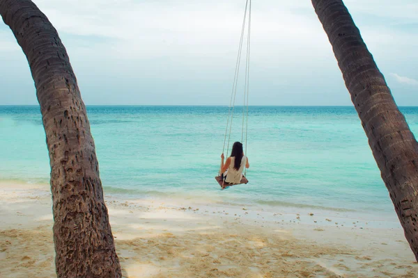 Swing on a palm tree. Beautiful island landscape with relaxing girl on a swing.