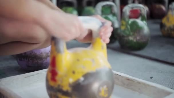 Joven atleta se está preparando para el entrenamiento con kettlebell. Chica frota kettlebell con magnesia para un buen agarre — Vídeo de stock