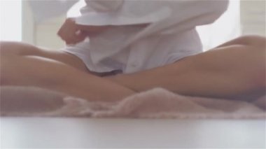Güzel bir genç kadın beyaz bir gömlek büyük salonunda katta oturuyor.