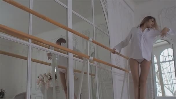 Hermosa joven en la ventana con una camisa blanca. bailando y relajándose en la sala de baile del ballet Barre — Vídeo de stock