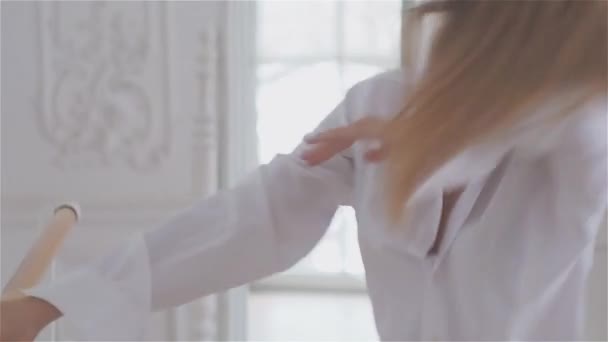 Красивая молодая женщина у окна в белой рубашке. танцы и отдых в танцевальном зале балета "Барре" — стоковое видео
