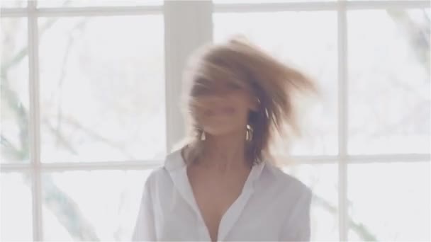 Piękna młoda kobieta w oknie w białej koszuli. taniec i relaks — Wideo stockowe