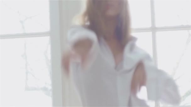 Красива молода жінка біля вікна в білій сорочці. танці та розслабляючі — стокове відео
