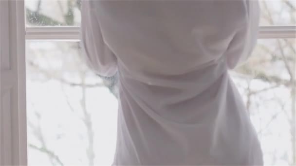 Красивая молодая женщина у окна в белой рубашке. танцы и отдых — стоковое видео