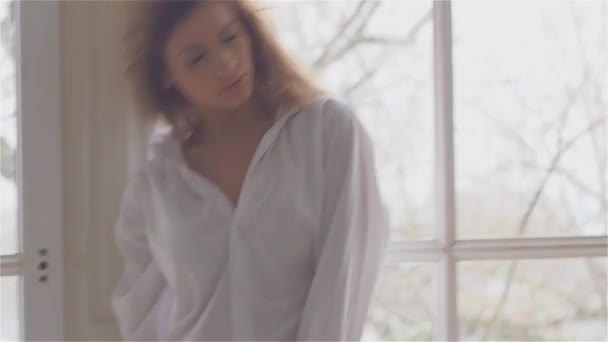 Beautiful young woman at the window in a white shirt. dancing and relaxing — Stock Video