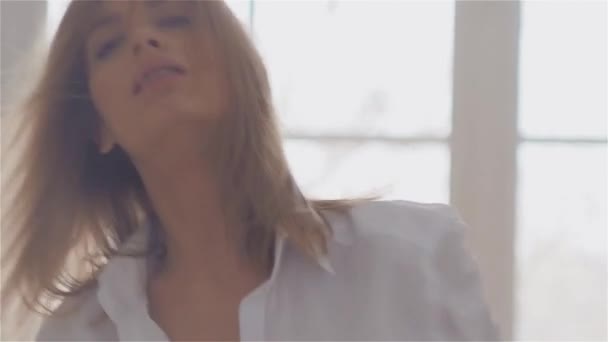 Schöne junge Frau am Fenster in einem weißen Hemd. Tanzen und Entspannen — Stockvideo