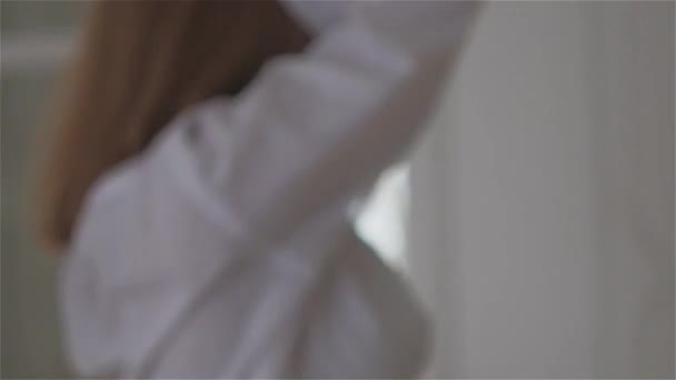 穿着白衬衫的美丽的年轻女子在窗边。跳舞和放松 — 图库视频影像