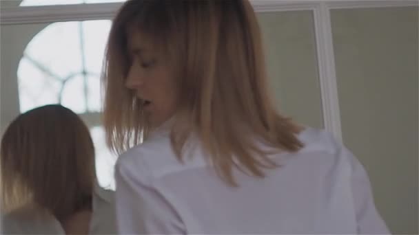 穿着白衬衫的美丽的年轻女子在窗边。跳舞和放松 — 图库视频影像