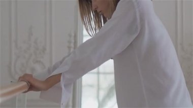 Beyaz bir gömlek penceresinde güzel genç kadın. dans ve bale Barre adlı dans salonunda rahatlatıcı