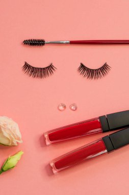 Kirpik, toz Kaş fırçası ve ruj güzel bir yüz olarak, pembe arka plan üzerinde kavramı.