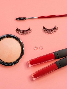 Kirpik, toz Kaş fırçası ve ruj güzel bir yüz olarak, pembe arka plan üzerinde kavramı.