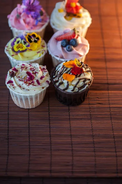 Hermosos y deliciosos cupcakes en la mesa. Un conjunto de deliciosos postres dulces —  Fotos de Stock