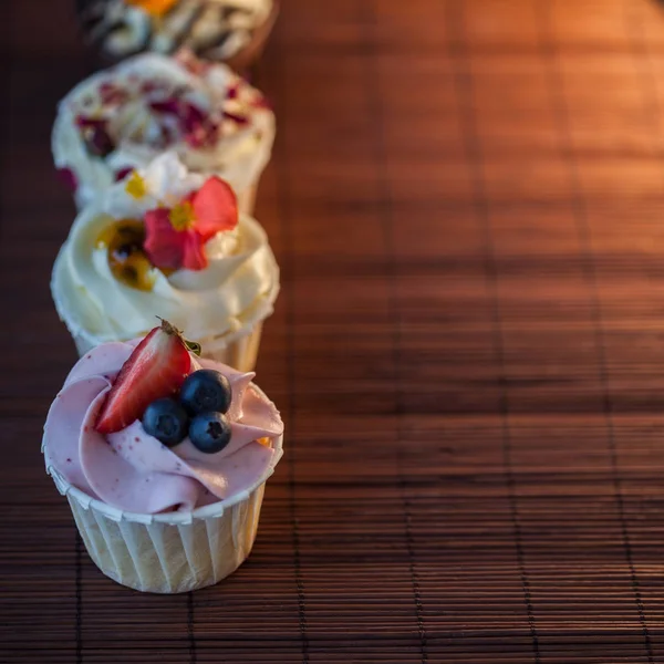 Bonitos e deliciosos cupcakes na mesa. Um conjunto de deliciosas sobremesas doces — Fotografia de Stock