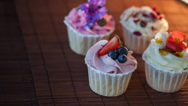 Hermosos y deliciosos cupcakes en la mesa. Un conjunto de deliciosos postres dulces —  Fotos de Stock