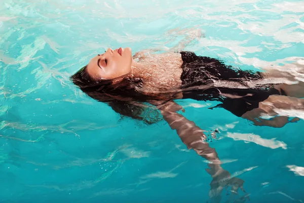 Joven hermosa y delgada mujer nada en la piscina sola. Spa y relajación, hotel de lujo — Foto de Stock