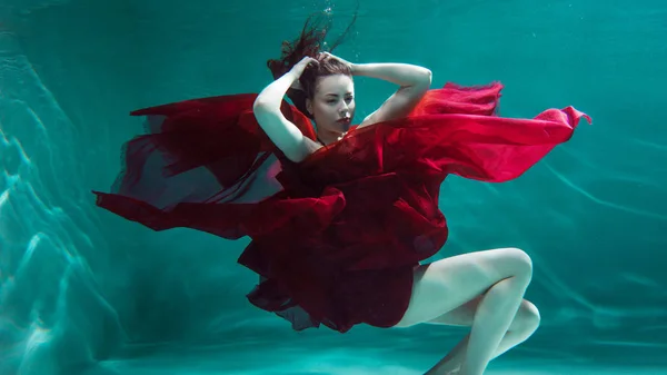 Portrait sous-marin mystique d'une belle jeune femme en robe rouge. Fille nager sous l'eau — Photo