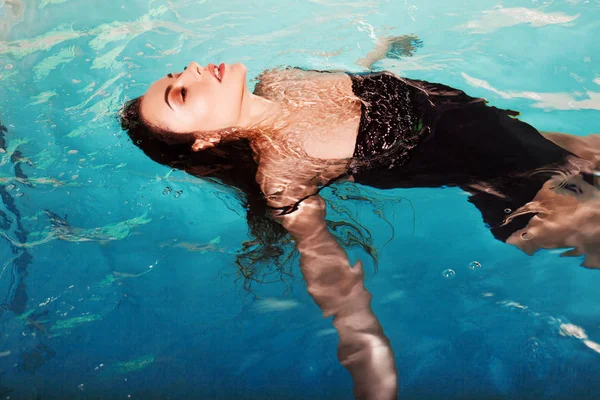 Счастливая юная красавица плавает в бассейне одна. Спа и релаксация, роскошный отель — стоковое фото