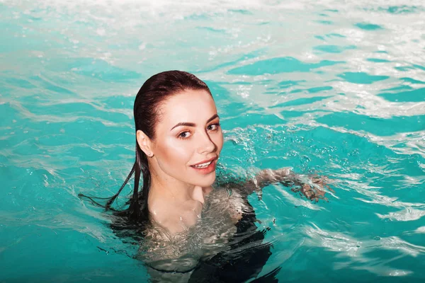 La joven y feliz belleza nada sola en la piscina. Spa y relajación, hotel de lujo —  Fotos de Stock