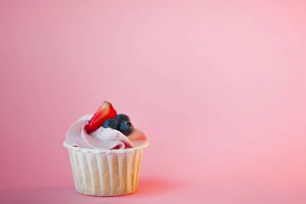 Süßes Dessert auf rosa Hintergrund, Kopierraum. Cupcake mit Sahne, schön und lecker. — Stockfoto