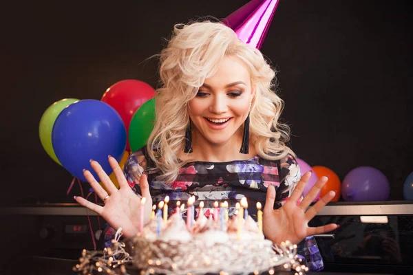 Urodziny, młoda kobieta wieje świece na jej tort urodzinowy. — Zdjęcie stockowe