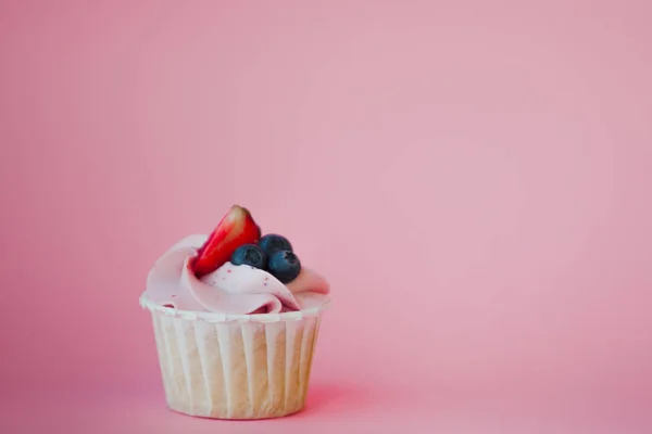 Süßes Dessert auf rosa Hintergrund, Kopierraum. Cupcake mit Sahne, schön und lecker. — Stockfoto