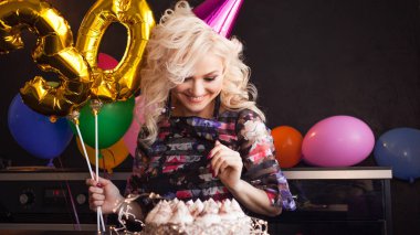 Mutlu genç kadın doğum günü partisinde eğleniyor. Büyüleyici ve çekici ve şenlikli pasta.