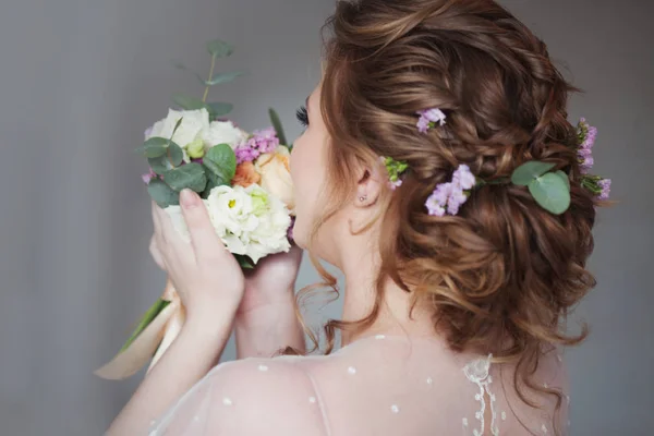 Mooie en elegante bruiloft kapsel. Jonge bruid met boeket bloemen — Stockfoto